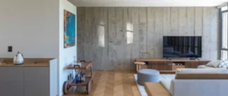 Obývacia izba využíva jednu z odhalených betónových stien ako pozadie pre pohodlné posedenie
