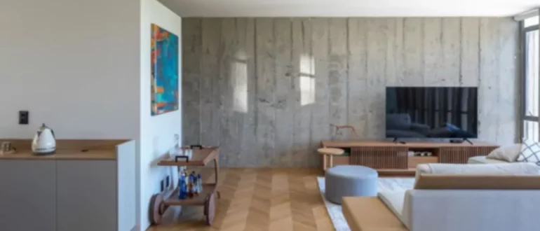 Il soggiorno utilizza una delle pareti in cemento a vista come sfondo per la sua confortevole area salotto