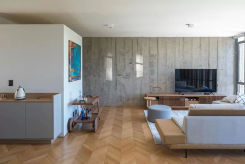 Obývacia izba využíva jednu z odhalených betónových stien ako pozadie pre pohodlné posedenie
